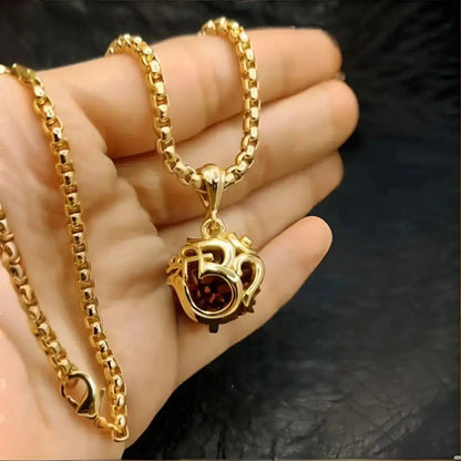 Gold necklace with a pendant held in a hand against a dark background