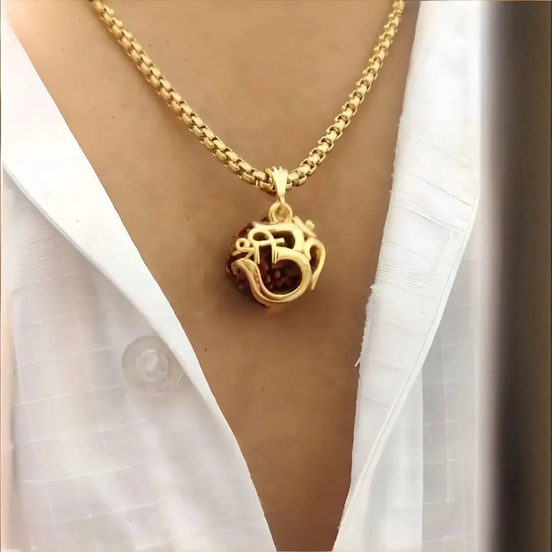 Gold necklace with a pendant worn by a person wearing a white shirt.