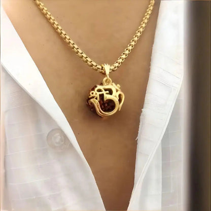 Gold necklace with a pendant worn by a person wearing a white shirt.