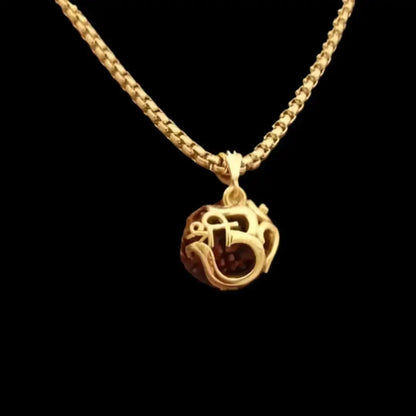 Gold necklace with a detailed pendant on a black background